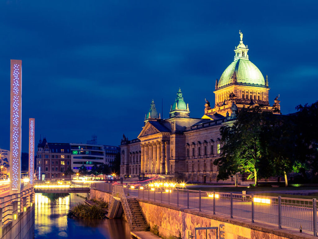Beleuchtetes Gebäude bei Nacht mit Wasser im Vordergrund.