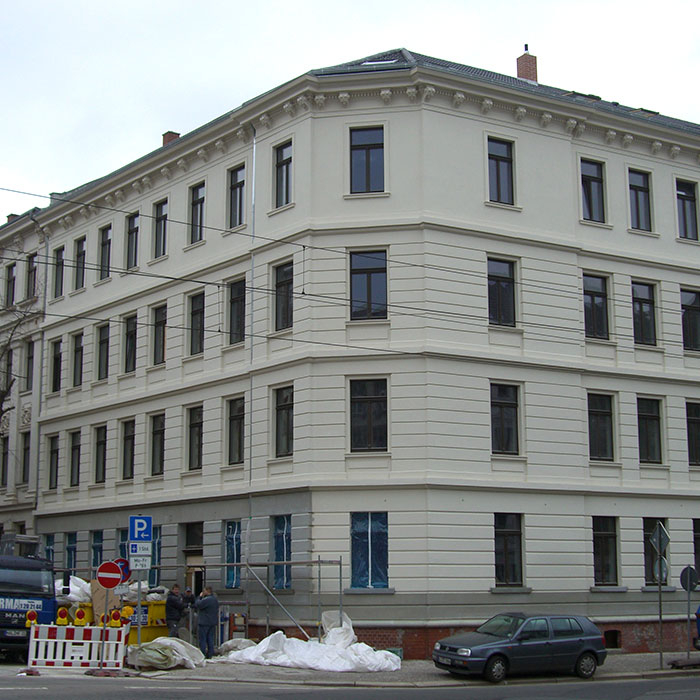 Eckgebäude mit Baustelle und parkendem Auto davor.