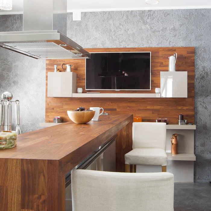 Moderne Küche mit Holztresen und Wandfernseher.