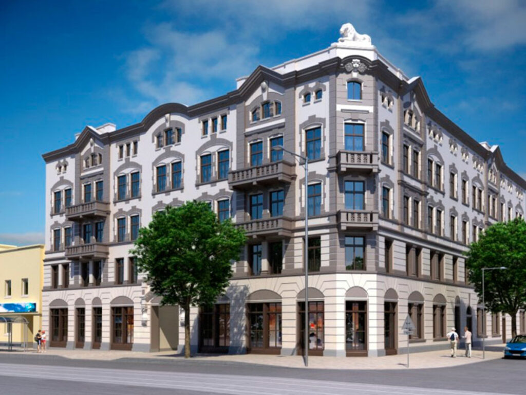Historisches Gebäude mit Erkern und Bäumen an Straßenecke.