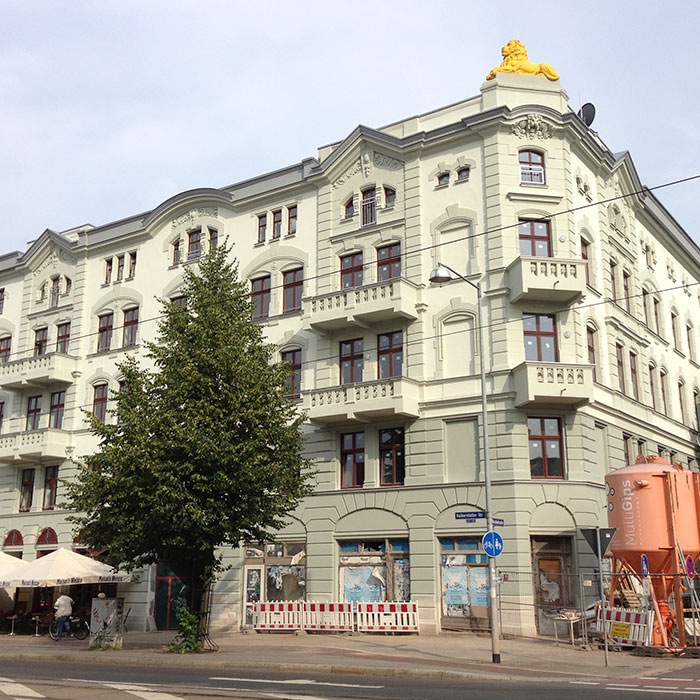 Historisches Gebäude mit Balkonen und Baum davor.