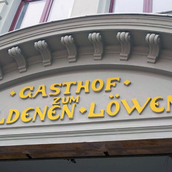 Fassade mit gelbem Schriftzug "Gasthof zum Goldenen Löwen".